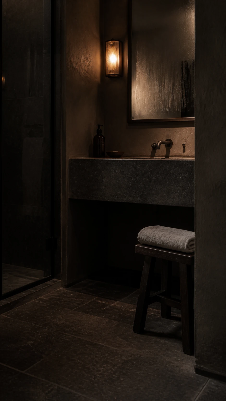 Bagno scuro in pietra con specchio appannato e telo di lino